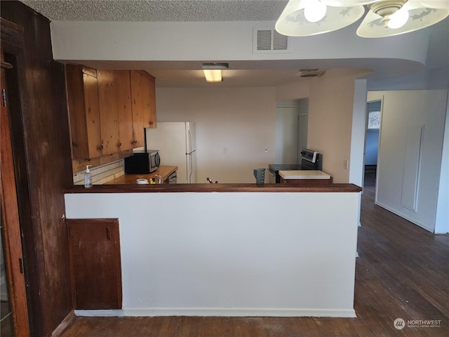 kitchen featuring kitchen peninsula, a textured ceiling, stainless steel appliances, and dark hardwood / wood-style floors