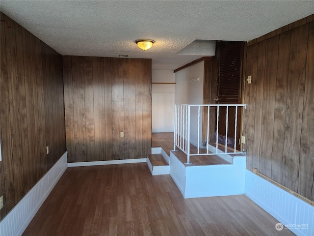 empty room with wood walls, wood-type flooring, and a textured ceiling