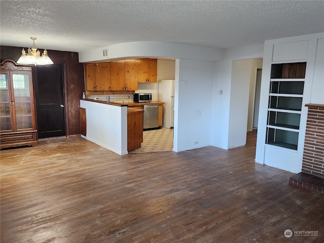 kitchen featuring an inviting chandelier, hanging light fixtures, hardwood / wood-style flooring, appliances with stainless steel finishes, and kitchen peninsula