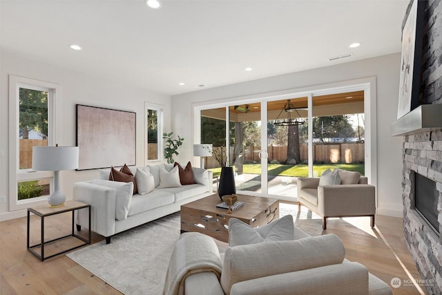 living room with recessed lighting, a fireplace, visible vents, baseboards, and light wood-style floors