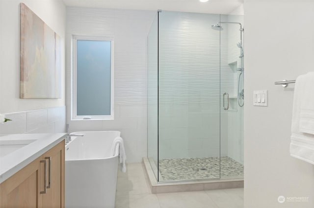 bathroom with tile walls, vanity, independent shower and bath, and tile patterned flooring