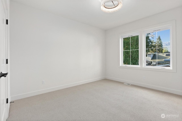 spare room featuring baseboards, visible vents, and light colored carpet