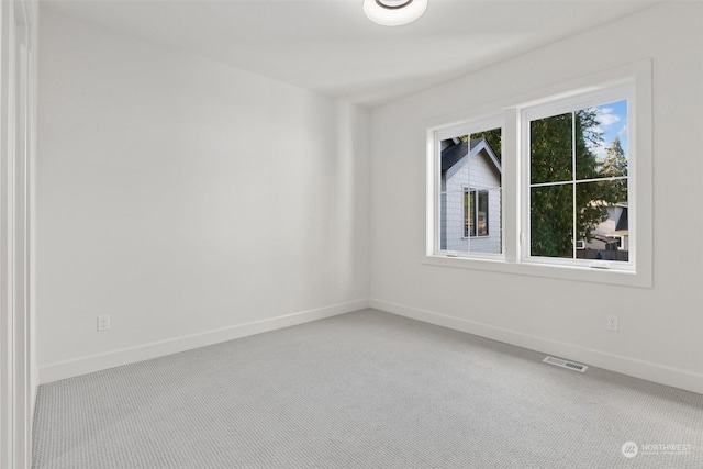 carpeted spare room featuring baseboards and visible vents