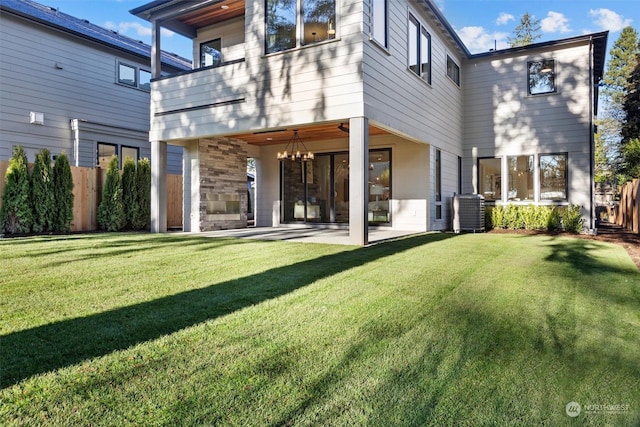 rear view of property with a balcony, fence, cooling unit, a yard, and a patio area