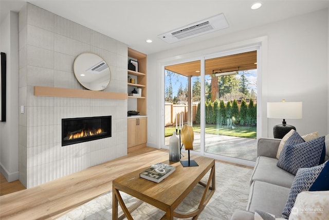 living room with light hardwood / wood-style floors and a tiled fireplace