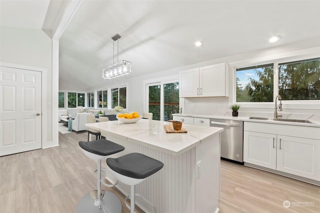 kitchen featuring pendant lighting, dishwasher, sink, vaulted ceiling, and a wealth of natural light