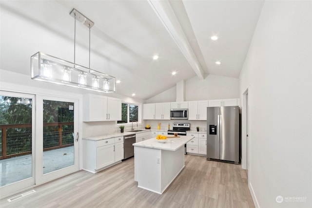 kitchen with stainless steel appliances, beam ceiling, light hardwood / wood-style flooring, white cabinets, and a kitchen island