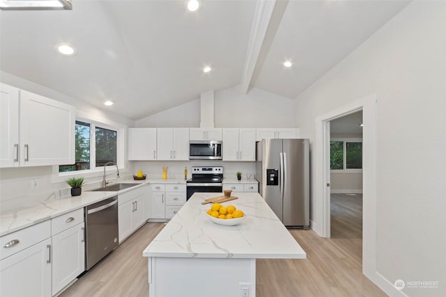 kitchen with appliances with stainless steel finishes, light wood-type flooring, a kitchen island, lofted ceiling with beams, and white cabinetry