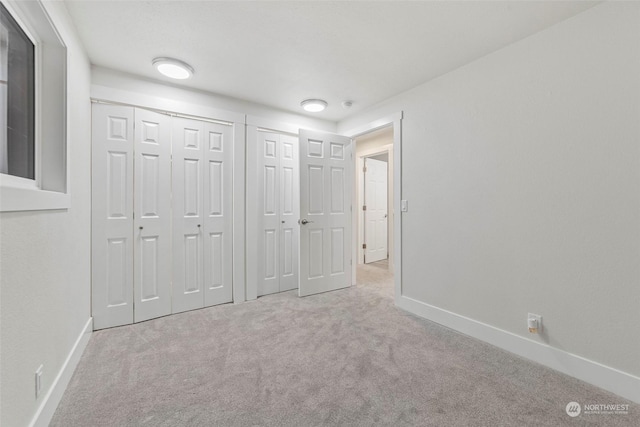 unfurnished bedroom with light colored carpet and two closets