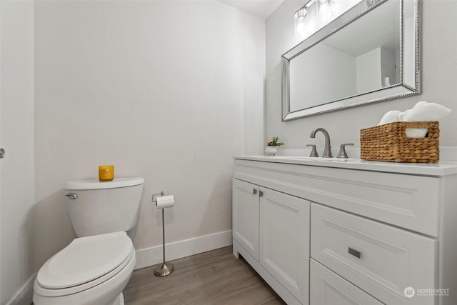 bathroom with hardwood / wood-style flooring, vanity, and toilet