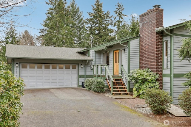 view of front of home with roof with shingles, a garage, driveway, and a chimney