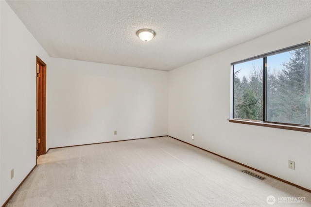 empty room with a textured ceiling, visible vents, and light carpet