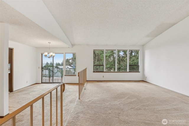 unfurnished room featuring light carpet, a textured ceiling, and an inviting chandelier