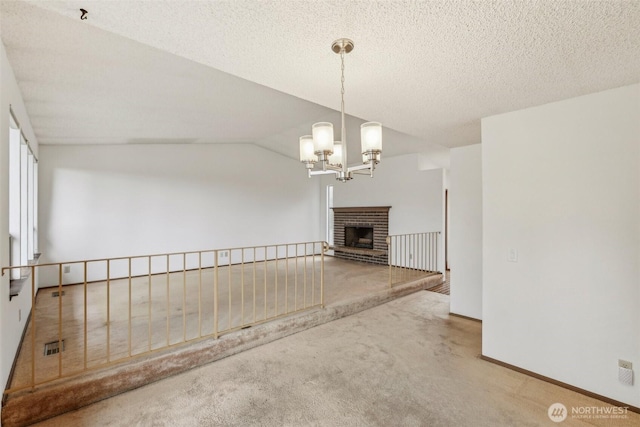 unfurnished living room featuring visible vents, a notable chandelier, a fireplace, carpet flooring, and lofted ceiling