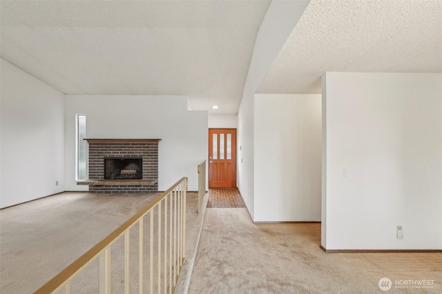 unfurnished living room with carpet, baseboards, a fireplace, recessed lighting, and a textured ceiling