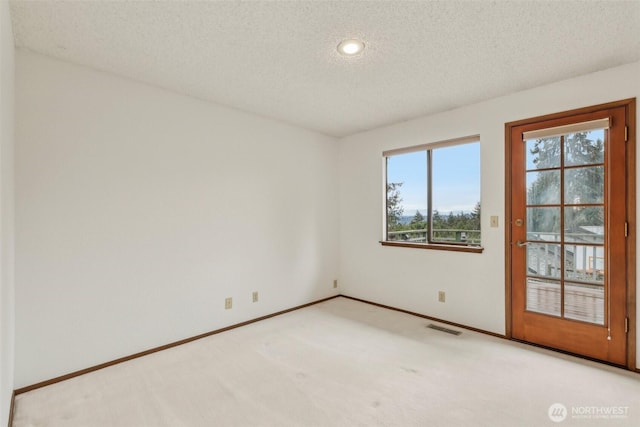 carpeted empty room with visible vents, baseboards, and a textured ceiling