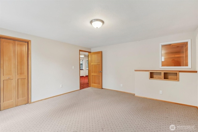 empty room with baseboards and light colored carpet