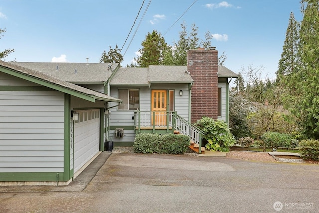 view of front of home with aphalt driveway, an attached garage, and a chimney