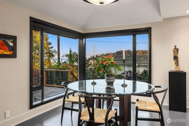 dining space featuring vaulted ceiling, a water view, baseboards, and a healthy amount of sunlight