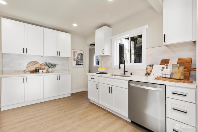 kitchen with stainless steel dishwasher, white cabinetry, sink, and light hardwood / wood-style flooring