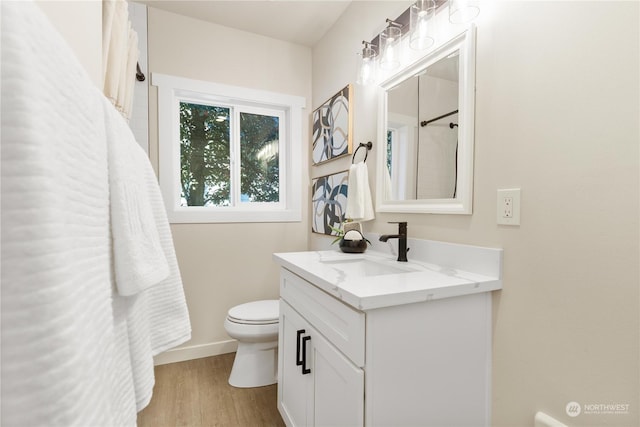 bathroom with hardwood / wood-style flooring, vanity, and toilet