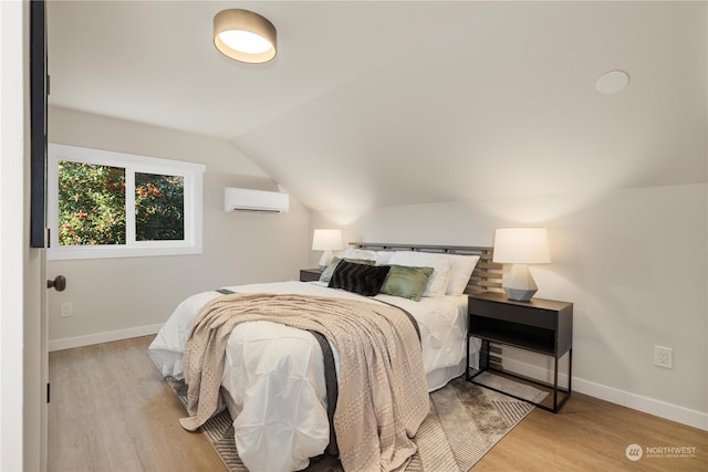 bedroom featuring lofted ceiling, light hardwood / wood-style flooring, and a wall mounted AC