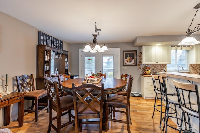 dining room featuring sink, light hardwood / wood-style flooring, and a notable chandelier