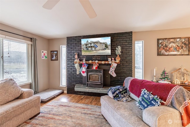 living room featuring hardwood / wood-style flooring, ceiling fan, a healthy amount of sunlight, and a wood stove