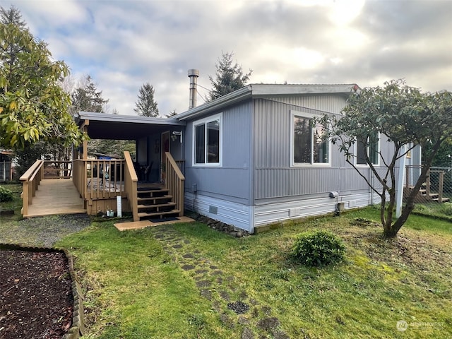 rear view of house featuring a lawn and a deck