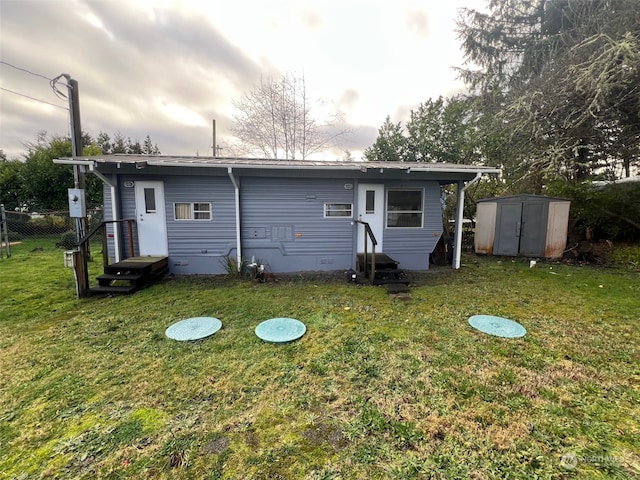 back of house with a lawn and a storage unit