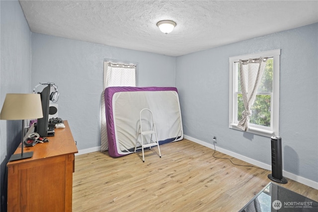 423 3rd Ave NE, Soap Lake, WA 98851 - bedroom featuring multiple windows, wood finished floors, a textured ceiling, baseboards, and a textured wall
