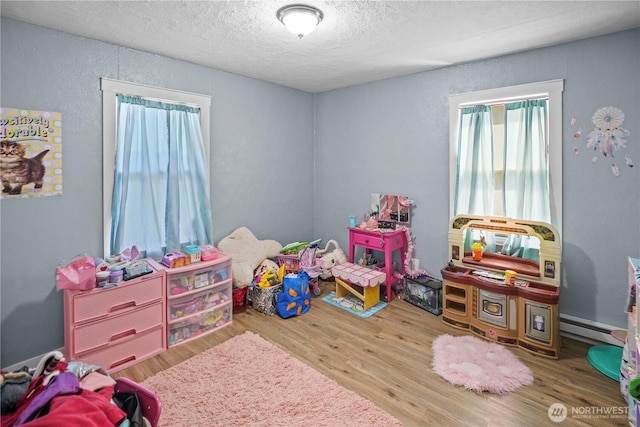 423 3rd Ave NE, Soap Lake, WA 98851 - playroom featuring a textured ceiling, wood finished floors, baseboard heating, and a textured wall
