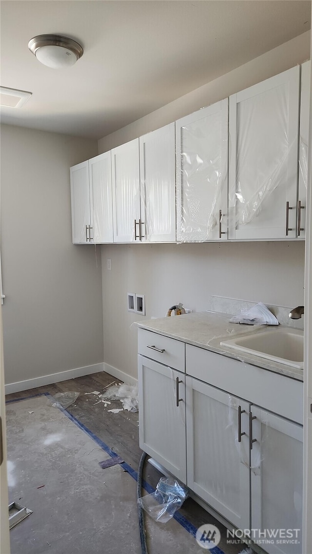 clothes washing area featuring cabinet space, baseboards, a sink, and hookup for a washing machine