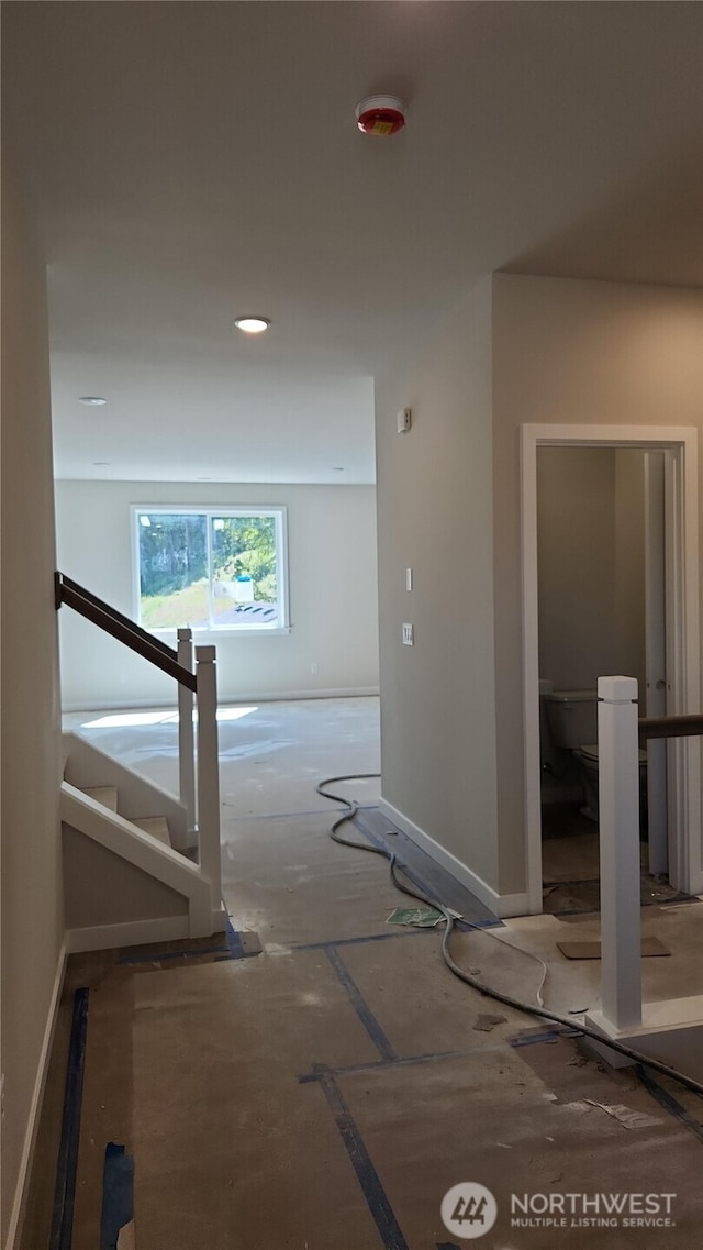 hallway featuring baseboards and stairway