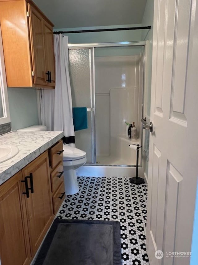 bathroom with tile patterned flooring, vanity, toilet, and a shower with shower door