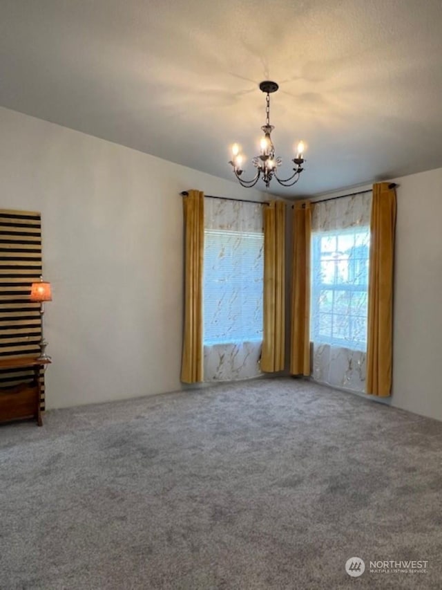 carpeted empty room with a chandelier