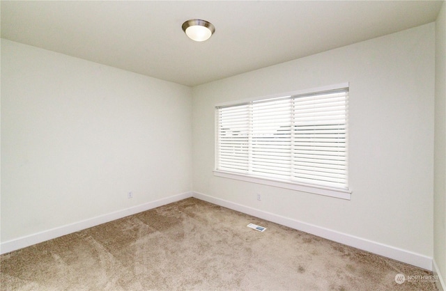 empty room with light carpet, visible vents, and baseboards