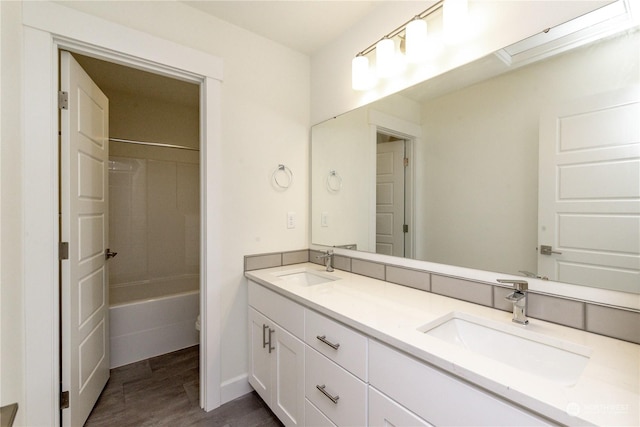 bathroom featuring double vanity, a sink, shower / tub combination, and wood finished floors