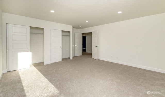 unfurnished bedroom featuring baseboards, recessed lighting, carpet flooring, and multiple closets