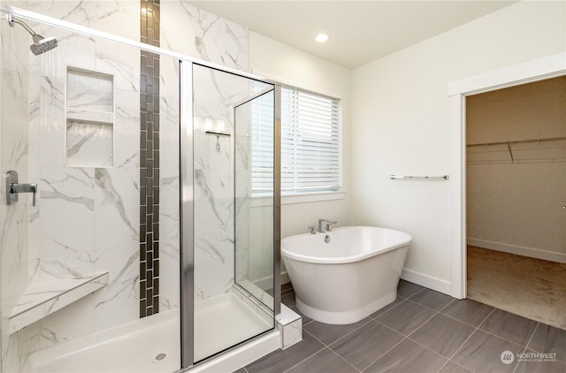 full bathroom featuring a soaking tub, baseboards, a spacious closet, and a marble finish shower