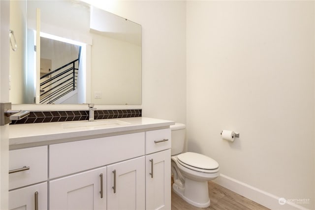 bathroom with toilet, baseboards, wood finished floors, and vanity