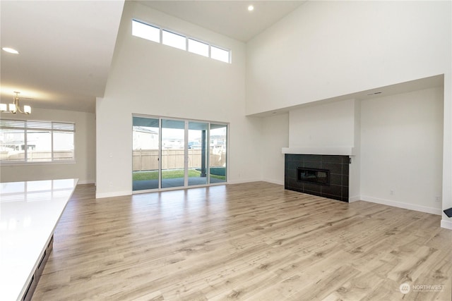 unfurnished living room with a fireplace, a high ceiling, and light hardwood / wood-style flooring