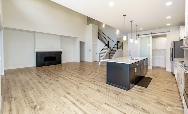 kitchen featuring a barn door, a tiled fireplace, light countertops, white cabinetry, and a sink