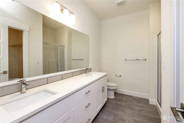 bathroom with hardwood / wood-style floors, vanity, an enclosed shower, and toilet