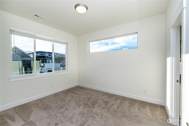 unfurnished room featuring carpet floors, visible vents, and baseboards