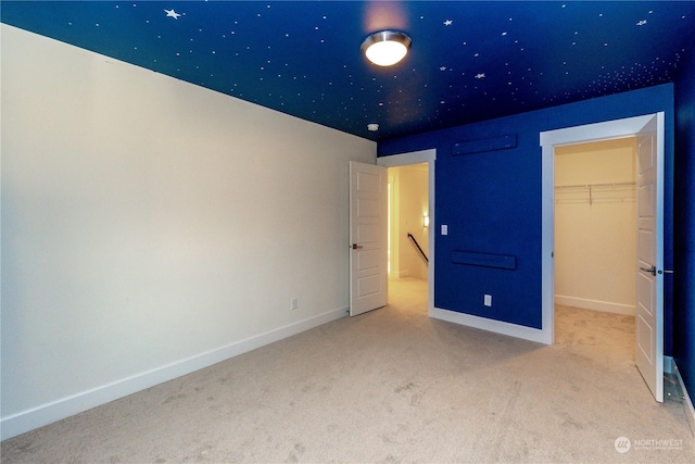 unfurnished bedroom featuring carpet flooring, a walk in closet, and a closet