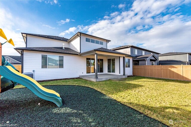 back of house featuring a patio, fence, a yard, a playground, and central AC