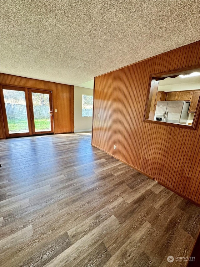 unfurnished room with hardwood / wood-style floors, a textured ceiling, and wooden walls