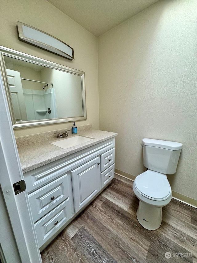 bathroom with a shower, toilet, vanity, and hardwood / wood-style flooring