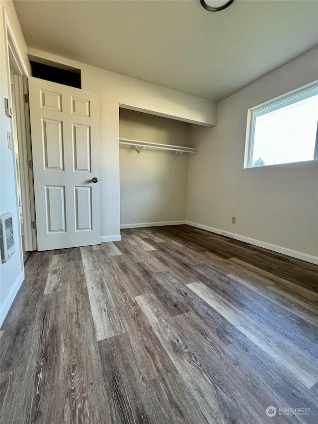 unfurnished bedroom featuring dark hardwood / wood-style flooring, a closet, and heating unit